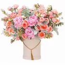 Pink peonies, coral roses, and succulents in a blush pink box with a gold tassel.