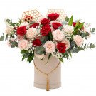 Round box of red and cream roses with decorative bamboo elements and gold tassel.