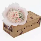 Bouquet of pink roses and baby's breath in a cardboard box.