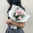 A bouquet of pink roses and eucalyptus wrapped in white paper.
