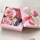 Pink gift box with faux roses and a MAC lipstick inside, tied with ribbons.