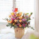 Wooden box of peach and purple roses, purple orchids, and mini lanterns.