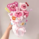 Pink Loopy plush toys bouquet with flowers and ribbons, held by a hand.