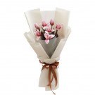 Bouquet of pink tulips wrapped in cream paper with a brown ribbon.
