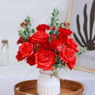Red roses and carnations in a white vase tied with twine.