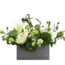 White and green floral arrangement in a grey box, featuring lotus pods, lilies, and roses.