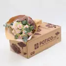 A pink rose bouquet and eucalyptus arranged on a cardboard flower box.