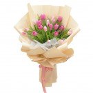 Pink and light pink tulips in a bouquet wrapped in cream and tan paper with a pink ribbon.