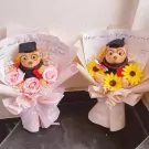 Two graduation bear bouquets with pink roses and sunflowers, wrapped in pale pink and cream paper.