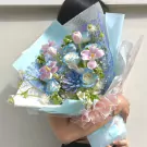Bouquet of pink tulips, blue roses, succulents, and orchids in pastel blue and pink wrapping.