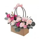 Box arrangement of pink and cream roses with carnations and eucalyptus.