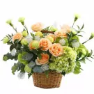 Basket arrangement of peach roses, green carnations, and hydrangeas.