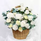 Basket of white roses, carnations, and greenery.