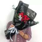 Bouquet of red roses wrapped in black paper with silver ribbon.