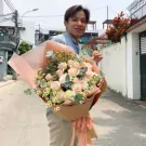 Man holding large pink and white rose bouquet with yellow accents.