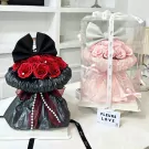 Two bouquets of roses, one red in a black wrapper, the other pink in a clear box.