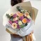 Bouquet with purple roses, orange David Austin roses, yellow gerberas, and white carnations.
