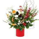 Christmas arrangement in a red vase with a snowman, pinecones, berries, and dried oranges.