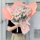 Pink rose bouquet with greenery and lavender accents, wrapped in peach and pink paper.