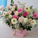Pink box of roses, gerberas, and baby's breath flowers, with a ribbon bow.