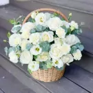 Basket of white roses, carnations, and lisianthus with eucalyptus.
