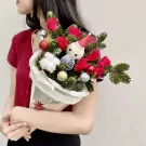 Christmas bouquet with red roses, pine branches, festive ornaments, and a cinnamon roll cone.
