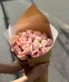 Bouquet of pink roses wrapped in brown paper and white tissue paper.