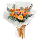 Bouquet of orange and pink roses with eucalyptus, wrapped in white paper and tied with an orange ribbon.