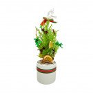 Small Christmas pine tree decorated with dried orange slices, cinnamon sticks, and green and red bows in a white ceramic pot.