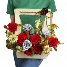 Flower basket with red and silver roses, yellow daisies, and gold accents, tied with a festive ribbon and pinecone.