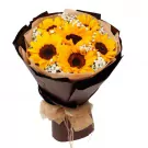 Bouquet of bright yellow sunflowers with baby's breath flowers, wrapped in dark brown paper and tied with burlap ribbon.