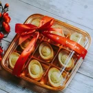 Gold bar shaped pineapple cakes in a gift box with a red ribbon.