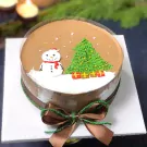 Chocolate mousse cake with snowman, Christmas tree, presents, and a satin ribbon bow.