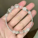 A delicate bracelet with pink rose quartz and clear quartz beads, accented with silver charms, resting on a hand.