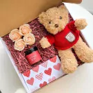 Gift box with teddy bear, soap roses, and candle.