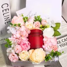 A red Hilton candle surrounded by pink and white flowers in a gift box.