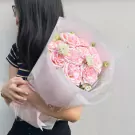 Woman holding a bouquet of pink Ohara roses with baby's breath.