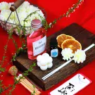 Reed diffuser, bubble candle, dried oranges, flowers, and matches on a wooden board.