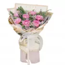 Pink peonies, baby's breath, and eucalyptus in newspaper-style wrapping with a white ribbon.