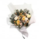 Bouquet of yellow, peach, and cream roses with greenery, wrapped in white paper.