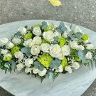 White roses and green filler flowers in a lush floral arrangement.