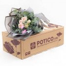 Bouquet of pink and white roses with eucalyptus on a cardboard box.