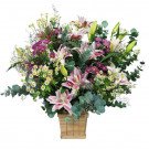 A wooden box filled with pink lilies, white daisies, purple flowers, and green eucalyptus leaves.