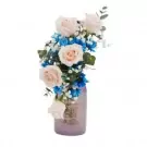 Bouquet of pink roses, blue chrysanthemums, and baby's breath in a purple vase.