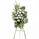 White funeral flower arrangement on a wooden easel.
