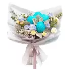 Bouquet of blue, white, and pastel flowers with greenery, wrapped in white paper and tied with a ribbon.