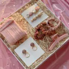Pink gift box with hair accessories: hair clips, scrunchies, claw clip, and earrings, plus pink socks.
