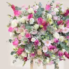 A large floral arrangement in shades of pink and white, featuring roses, carnations, and baby's breath.