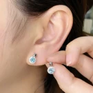 Silver stud earrings with blue topaz and star accents.