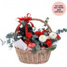 Fruit and flower basket with grapes, apples, red and white flowers, and eucalyptus, tied with a red ribbon.